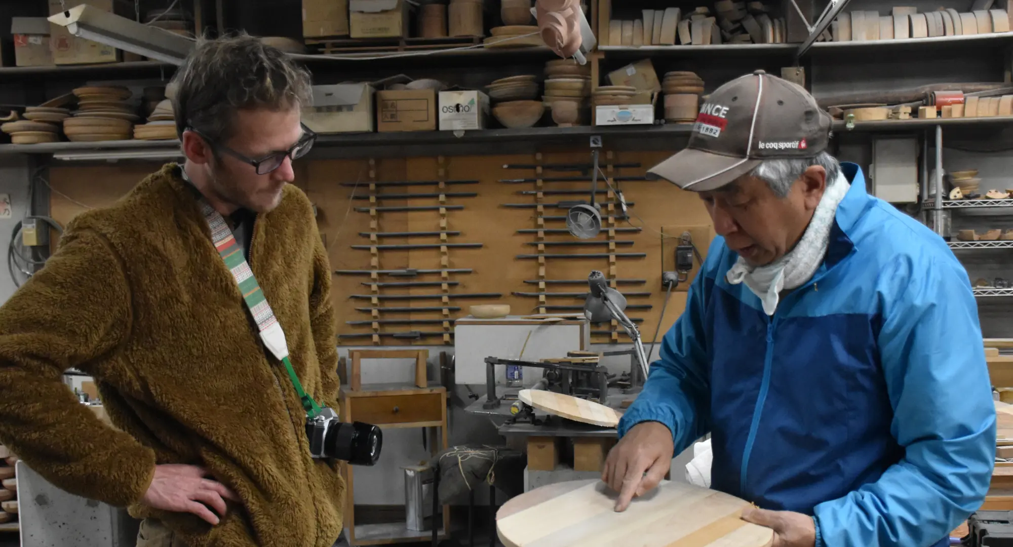 A Japanese man and a foreign man with a camera talking about timber