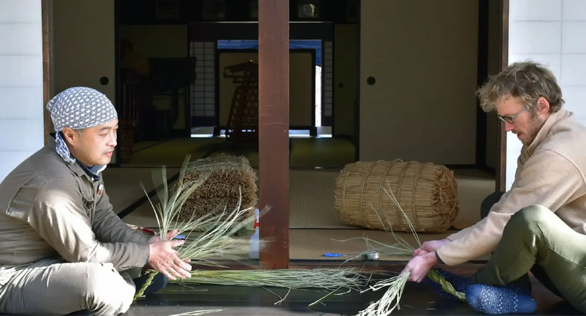 A Japanese man teaching a foreigner the art of creating ancient craft of Wara-Zaiku