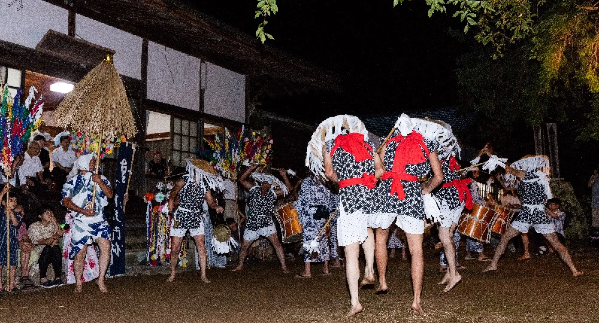 Men wearing yukata and umbrellas, dancing at a festival