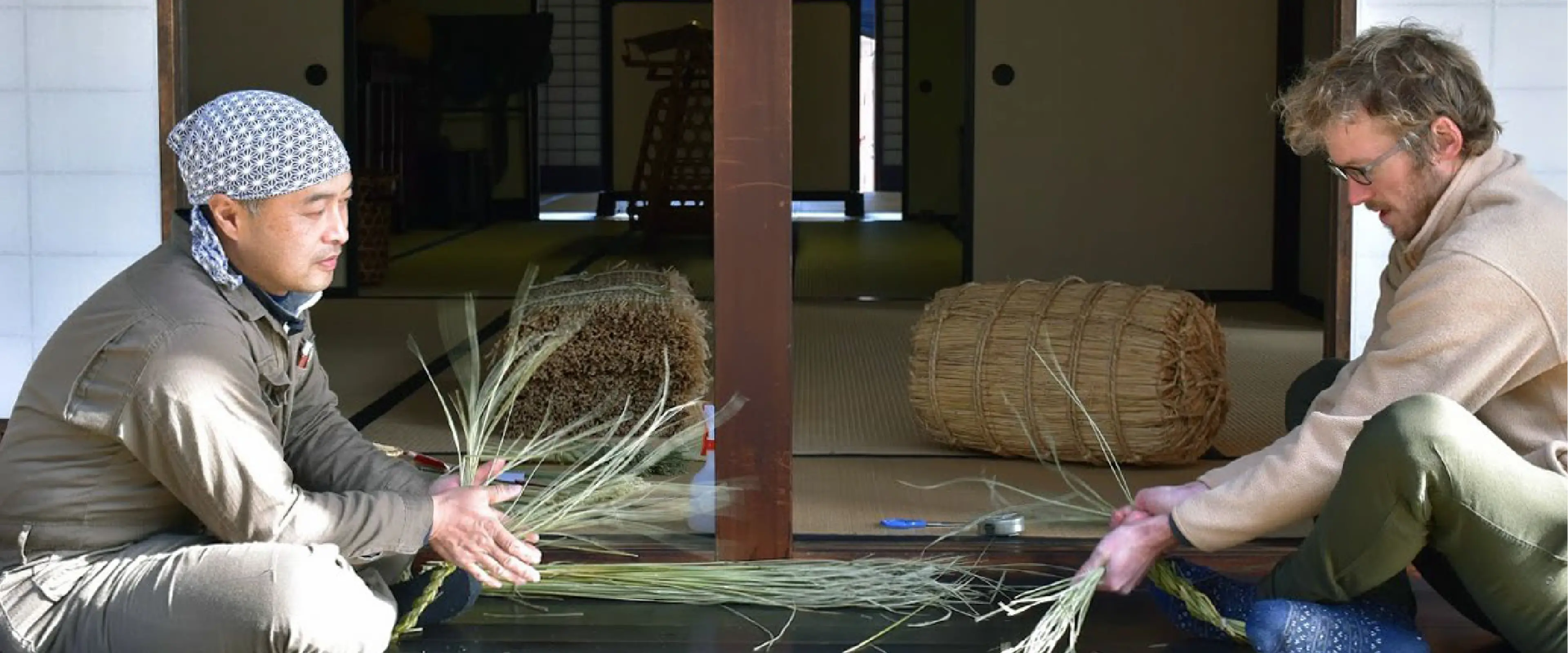 A Japanese man teaching a foreigner the art of creating ancient craft of Wara-Zaiku