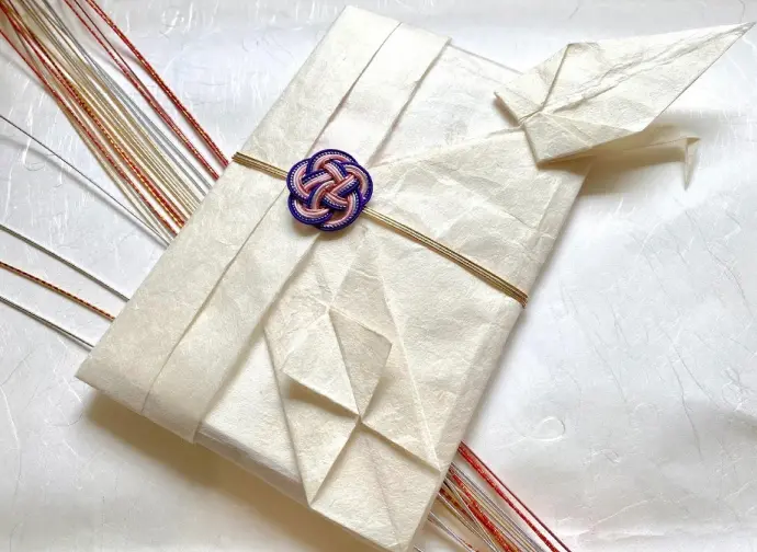 A crane made of white washi paper and a congratulatory envelope.