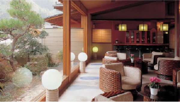 A cozy lounge area with woven chairs and a scenic view of a Japanese garden through large windows, creating a relaxing atmosphere.