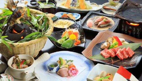 A beautifully arranged Japanese kaiseki meal, featuring grilled meats, fresh seafood, seasonal vegetables, and decorative plating for an elegant dining experience.