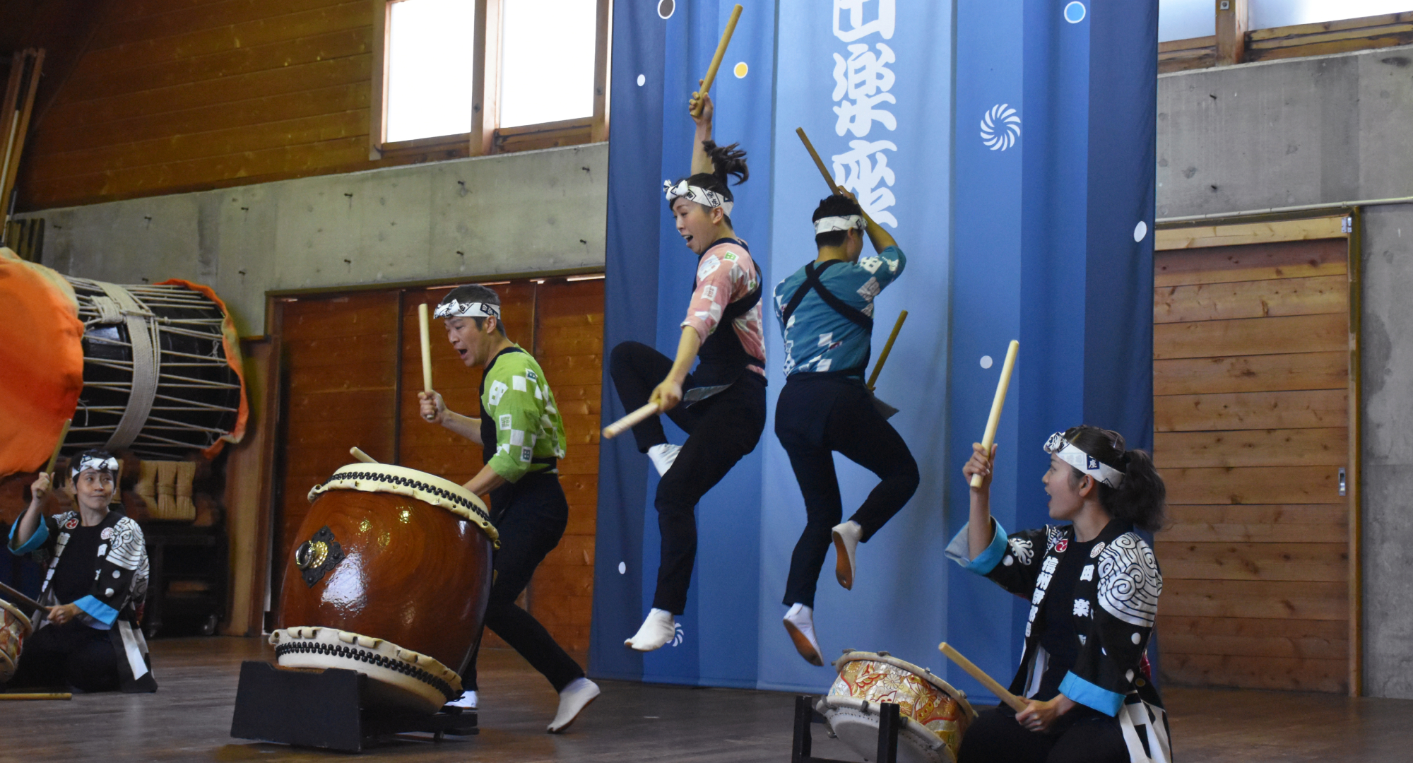 A dynamic Taiko drum performance with energetic drummers dressed in traditional attire, jumping as they play.
