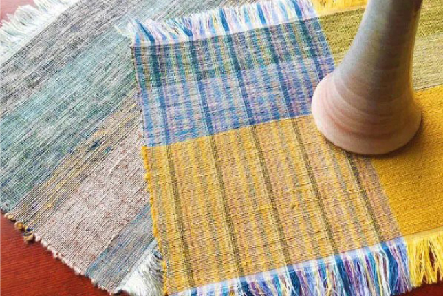 Two colorful handwoven silk placemats with intricate patterns, showcasing the craftsmanship of traditional textile weaving.