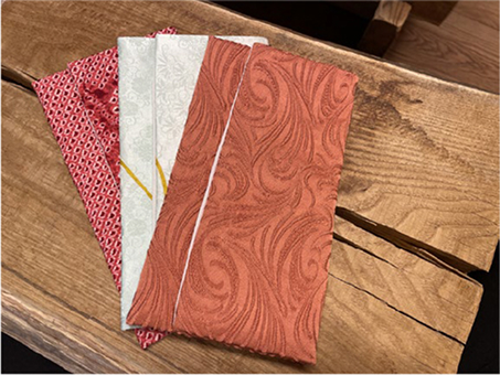 A set of elegantly designed fabric pouches placed on a rustic wooden surface. Each pouch features intricate patterns and traditional Japanese textile designs, evoking a sense of craftsmanship and cultural heritage.
